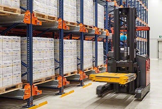 With a forklift, the operator picks up the pallet shuttle car and moves it to the assigned lane