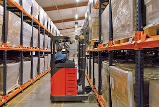 The forklift deposits the first pallet at the beginning of the lane of a push back warehouse racking system