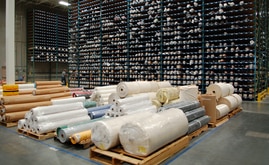 Extending imposingly 30 feet in the air, thousands of fabric rolls bunk in shelving compartments like crayons in a box